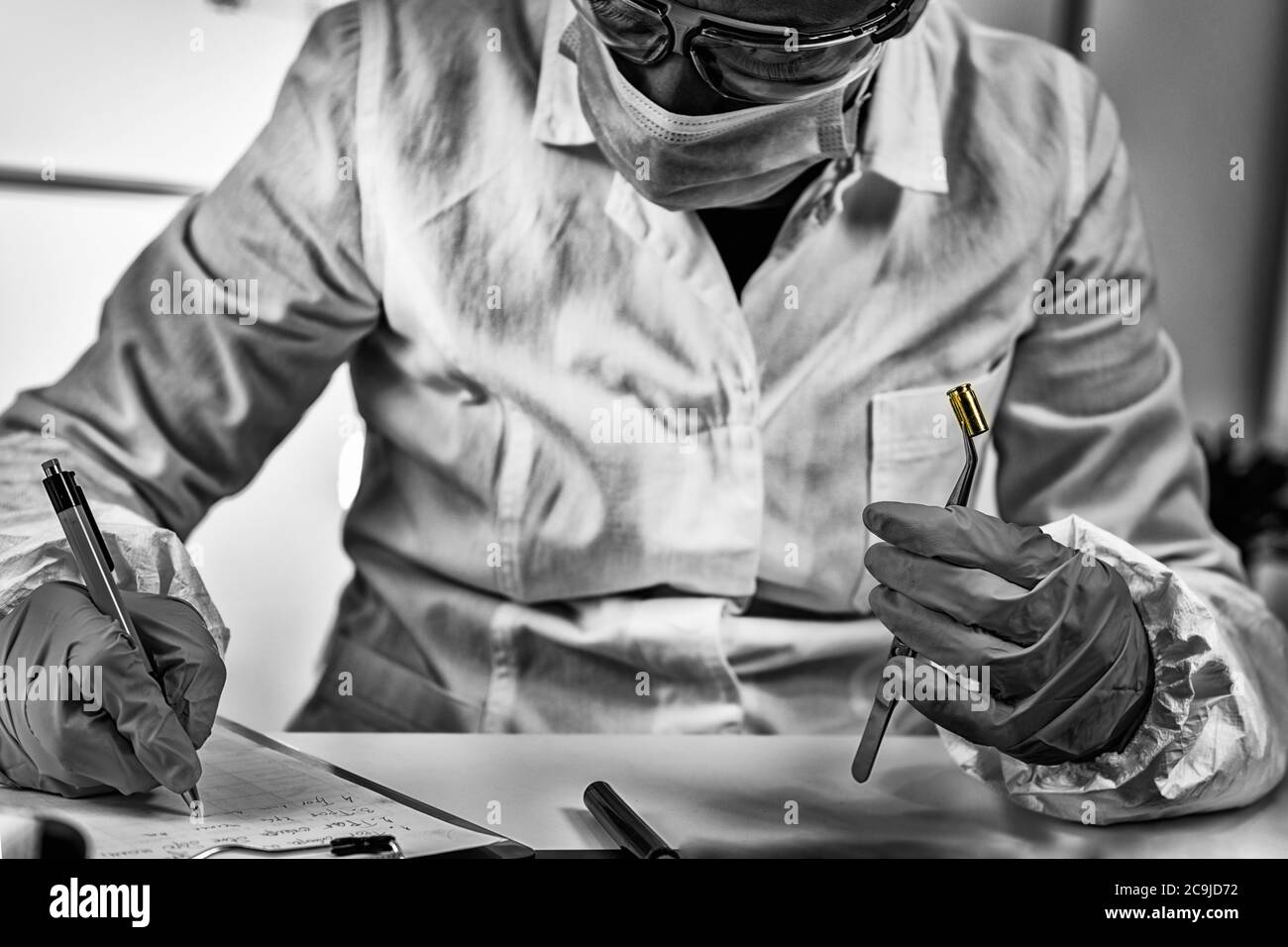 Forensische Wissenschaft im Labor. Forensischer Techniker, der das Geschossgehäuse untersucht. Stockfoto