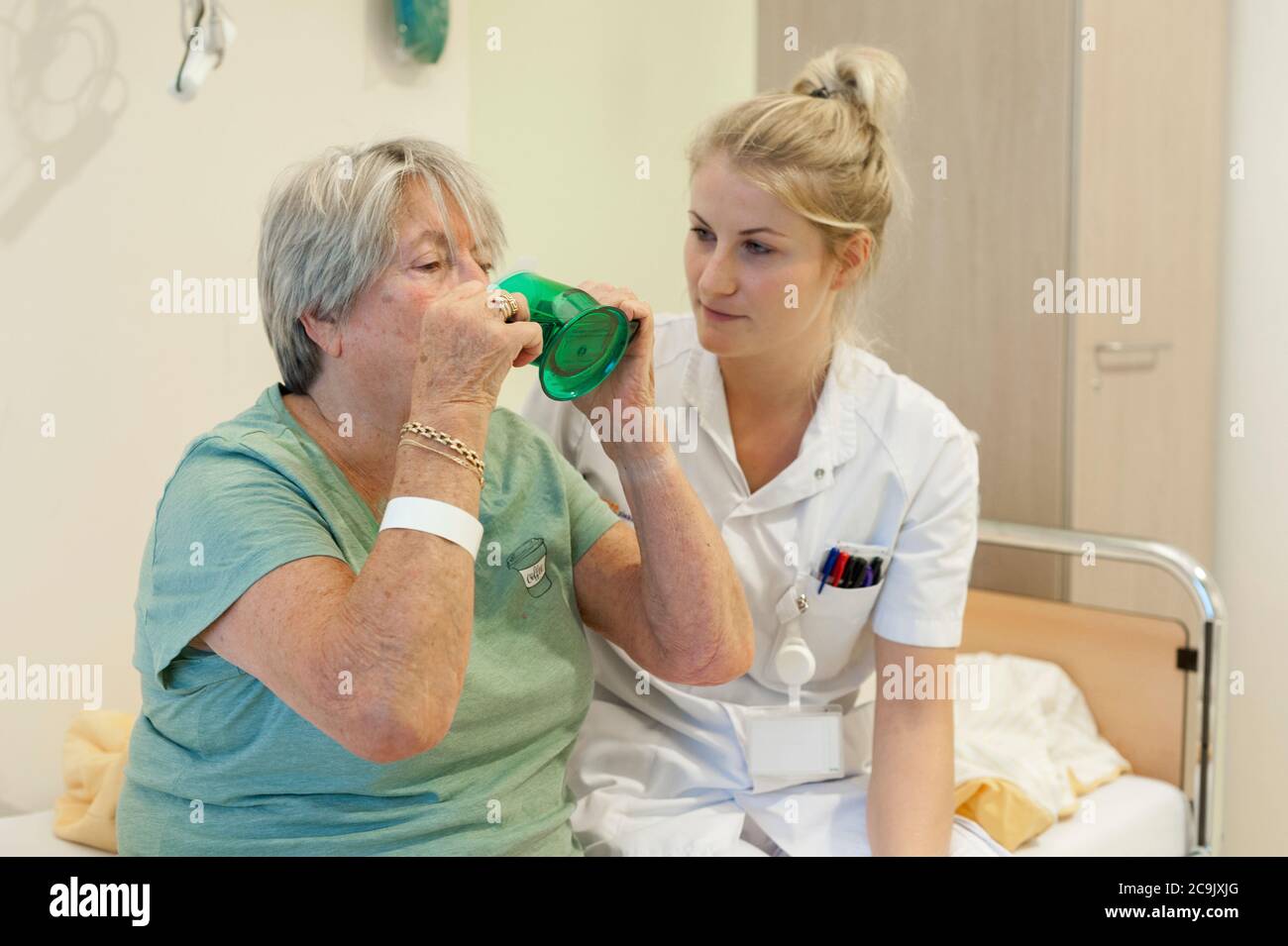 Geriatrische Krankenhausabteilung. Krankenschwester, die einem verwirrten Patienten auf der geriatrischen Abteilung eines Krankenhauses hilft. Stockfoto