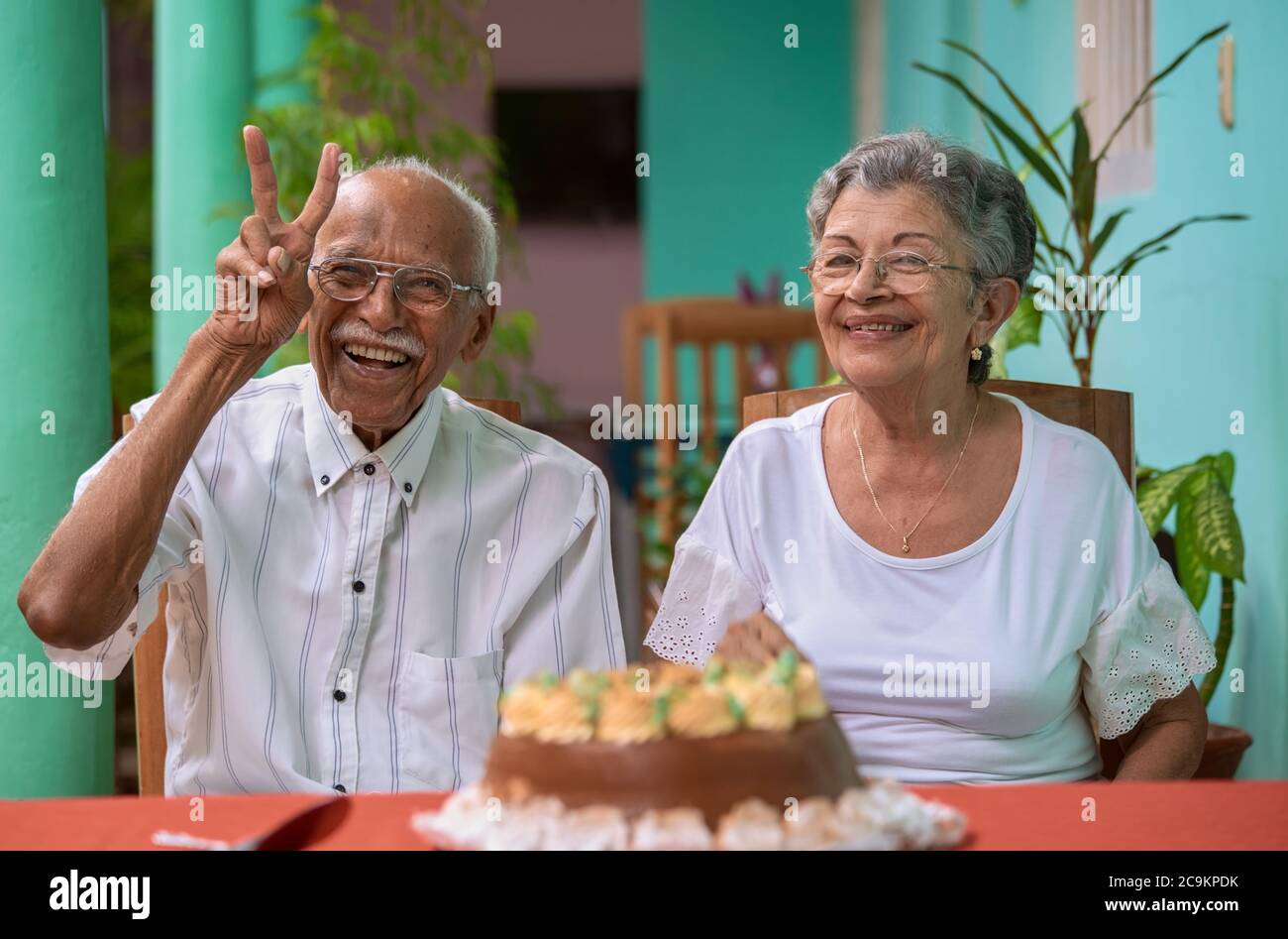 Lächelndes, älteres Paar, das vor einem Kuchen sitzt Stockfoto
