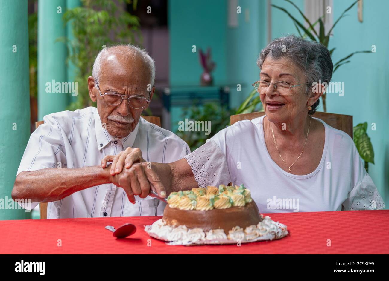 Lächelndes, älteres Paar, das sich gegenseitig einen Kuchen schneidet Stockfoto