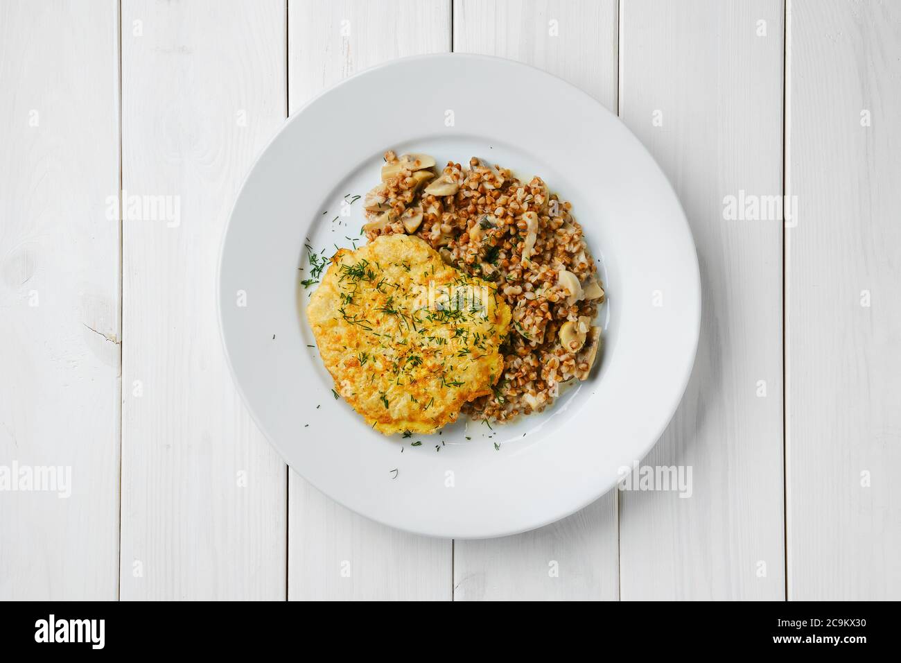 Draufsicht auf Hühnerschnitzel in Panade mit Buchweizen und Pilzen Stockfoto