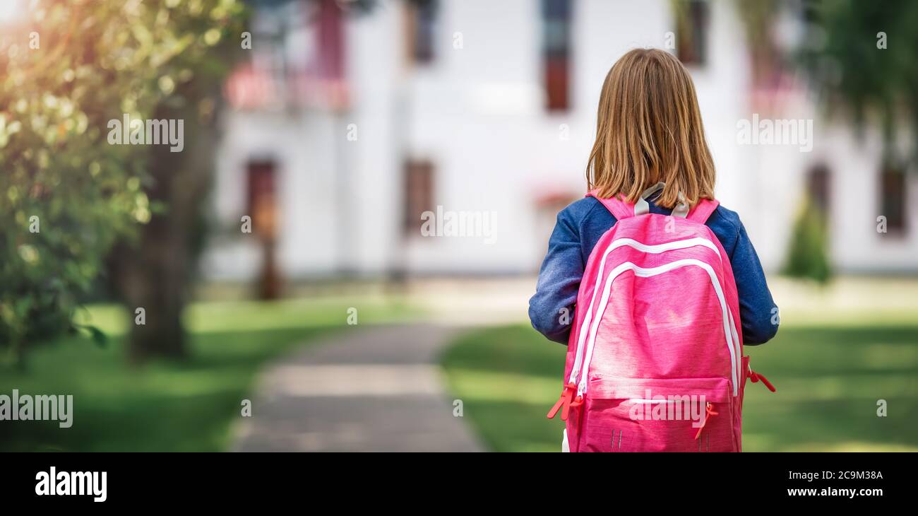 Mädchen mit Rucksack vor einer Schule Stockfoto