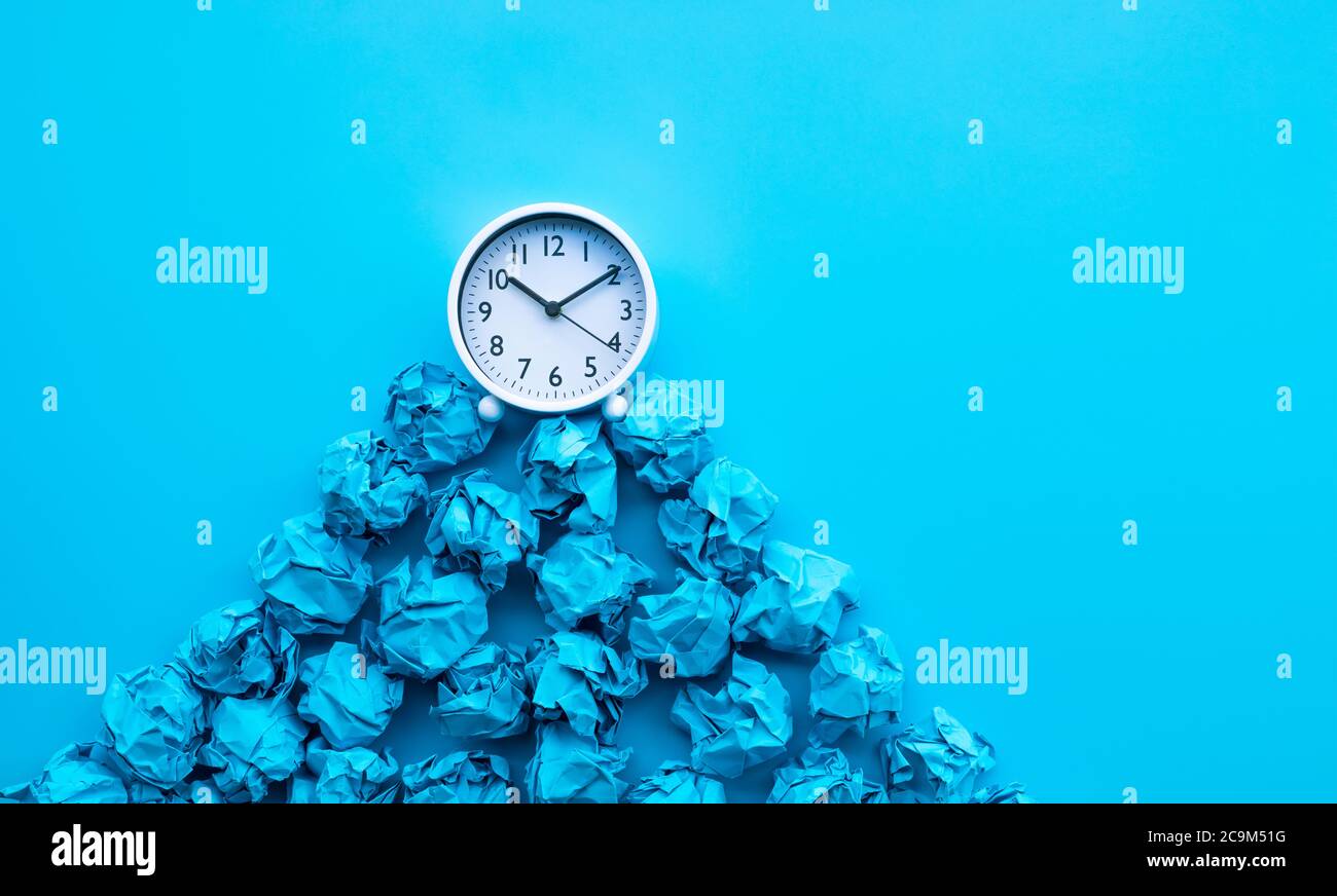 Timing und Denkidee mit Papier zerknittert Kugel und weiße Uhr. Business-Performance Stockfoto