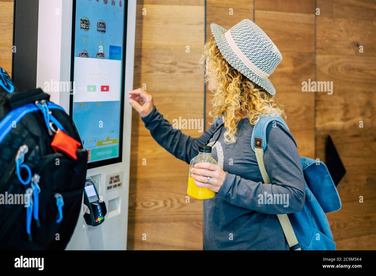 Eine Erwachsene Frau, die ihr Essen in einem Restaurant oder einer Bar mit einem Touchscreen-Händler in etwas Fast-Food - lockige Dame, die sich für das Essen zum Mittagessen Stockfoto