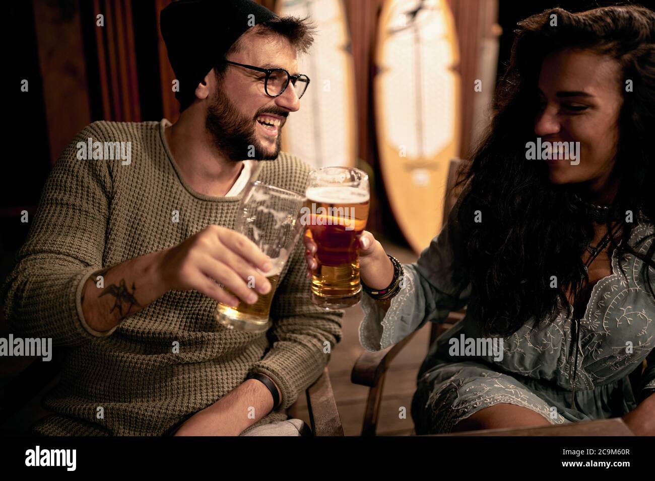 Lächelnder Mann und Frau genießen am Abend Spaß und trinkt Bier zusammen .pärchen trinken zusammen. Stockfoto