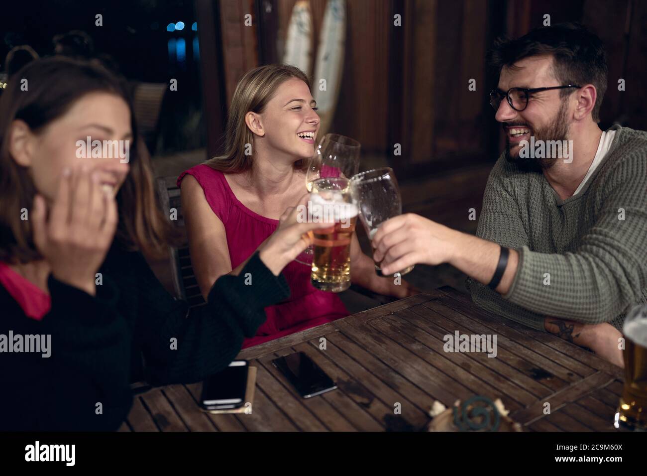 Lächelnder Mann und Frau genießen am Abend Spaß und trinkt Bier zusammen. Freunde genießen Getränke zusammen. Stockfoto