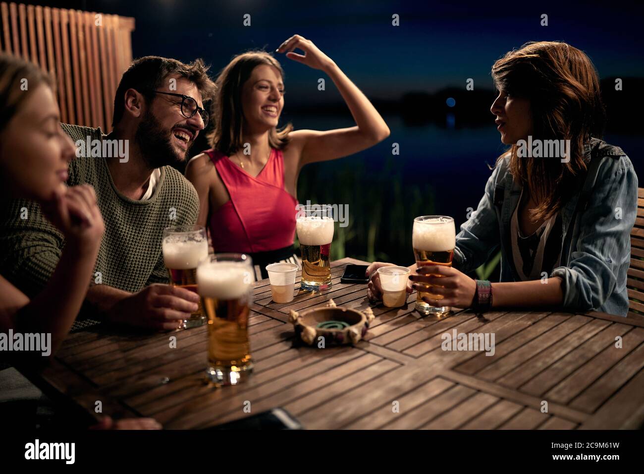 Lächelnde Freunde reden und trinken Bier und genießen einen schönen Abend. Stockfoto