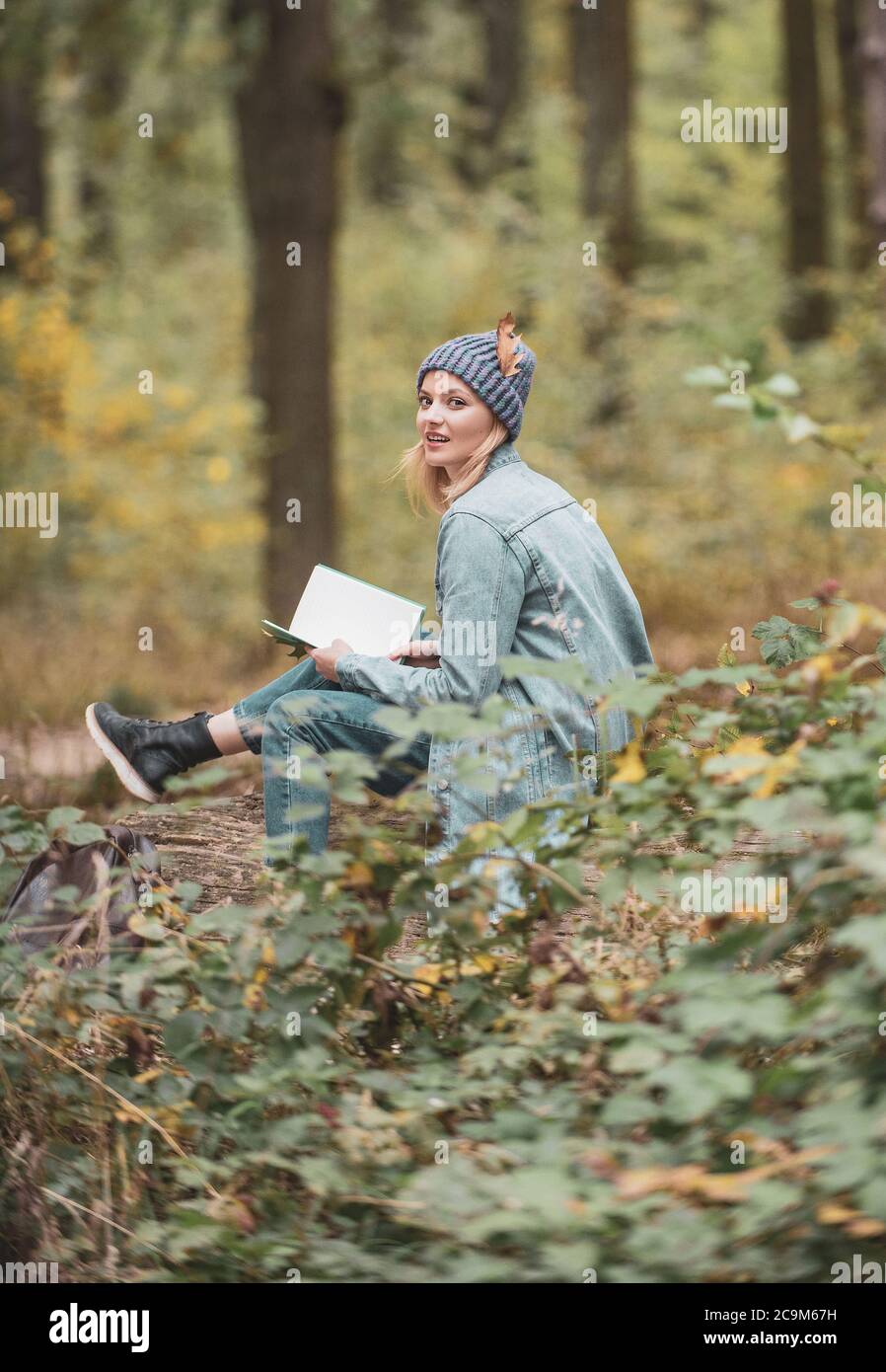 Frauen schreiben Notizen Herbst Naturlehrpfade, Wälder. Schriftstellerin. Herbststimmung. Mädchen mit Stift schreiben auf Notebook auf Gras draußen. Lesen Sie ein Buch Stockfoto