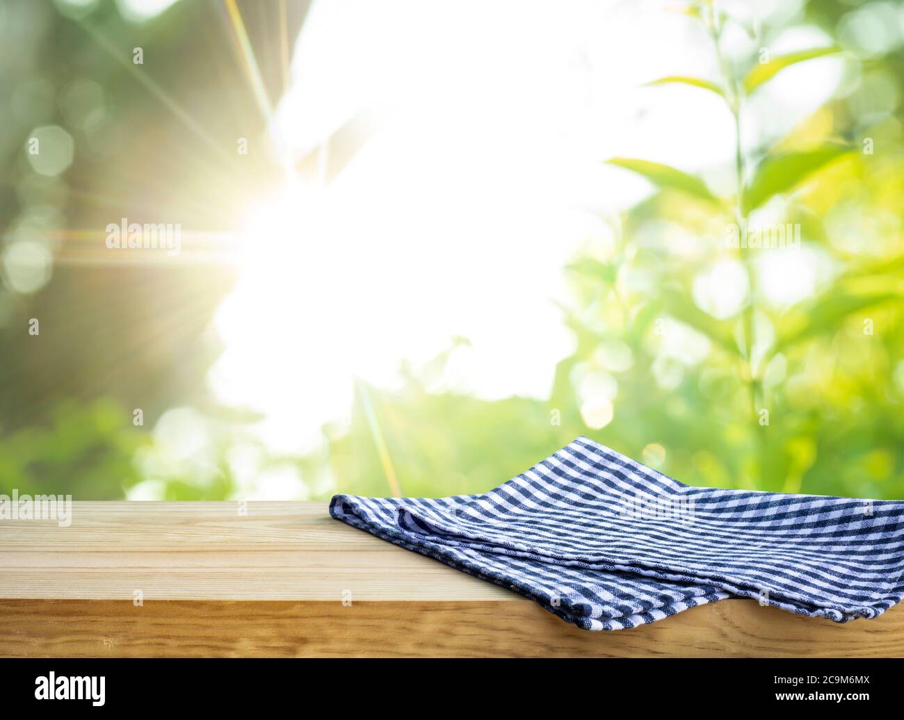 Blau karierte Tischdecke auf Holz mit verschwommenem grünen Bokeh von Baum Hintergrund.Sommer und Picknick-Konzepte.Design für wichtige visuelle Lebensmittel und Getränke Produkte. Stockfoto