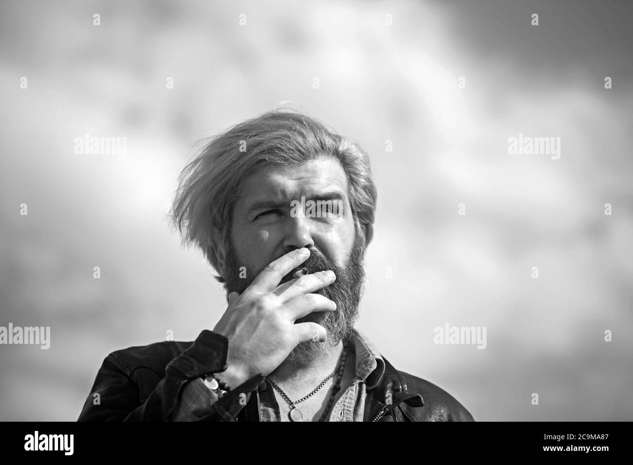 Mode Mann Rauchen auf Himmel Hintergrund. Mode Raucher mit Zigarette an der frischen Luft. Stockfoto