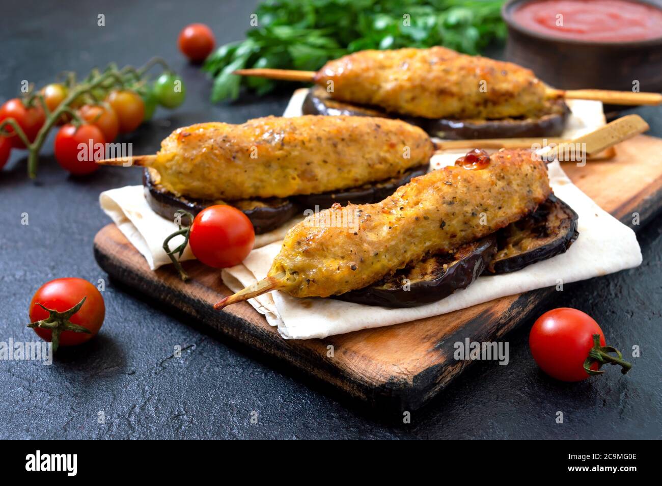 Lula Kebab mit gegrillter Aubergine auf Pita-Brot. Hähnchenkebab auf einem Spieß mit Gemüse auf dem schwarzen. Stockfoto