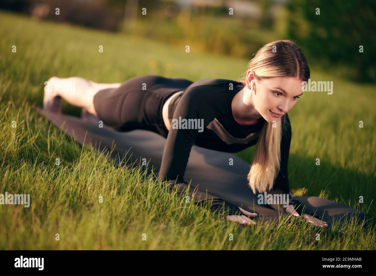 Athletische und starke Frau, die bei Sonnenuntergang in Plankenstellung im Freien steht. Konzept von Sport, Erholung und Motivation. Stockfoto