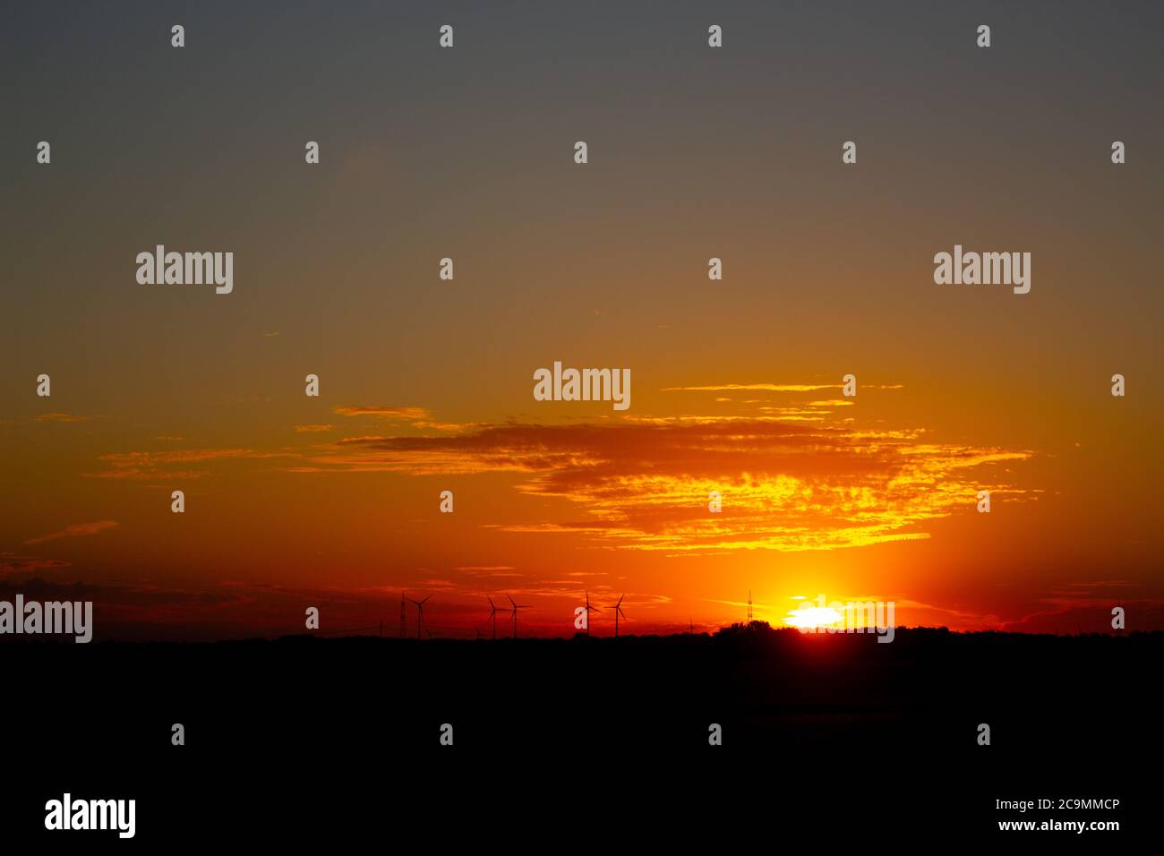 Sonnenaufgang mit Silhouetten von Windkraftanlagen am Horizont Stockfoto