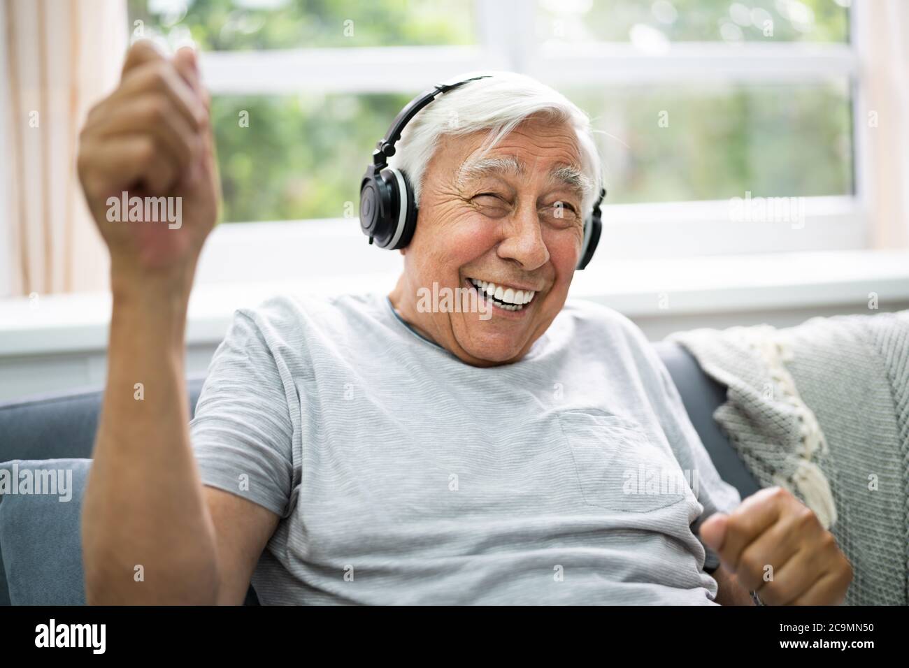 Lächelnd Ältere Senior Listening Musik Auf Kopfhörer Stockfoto