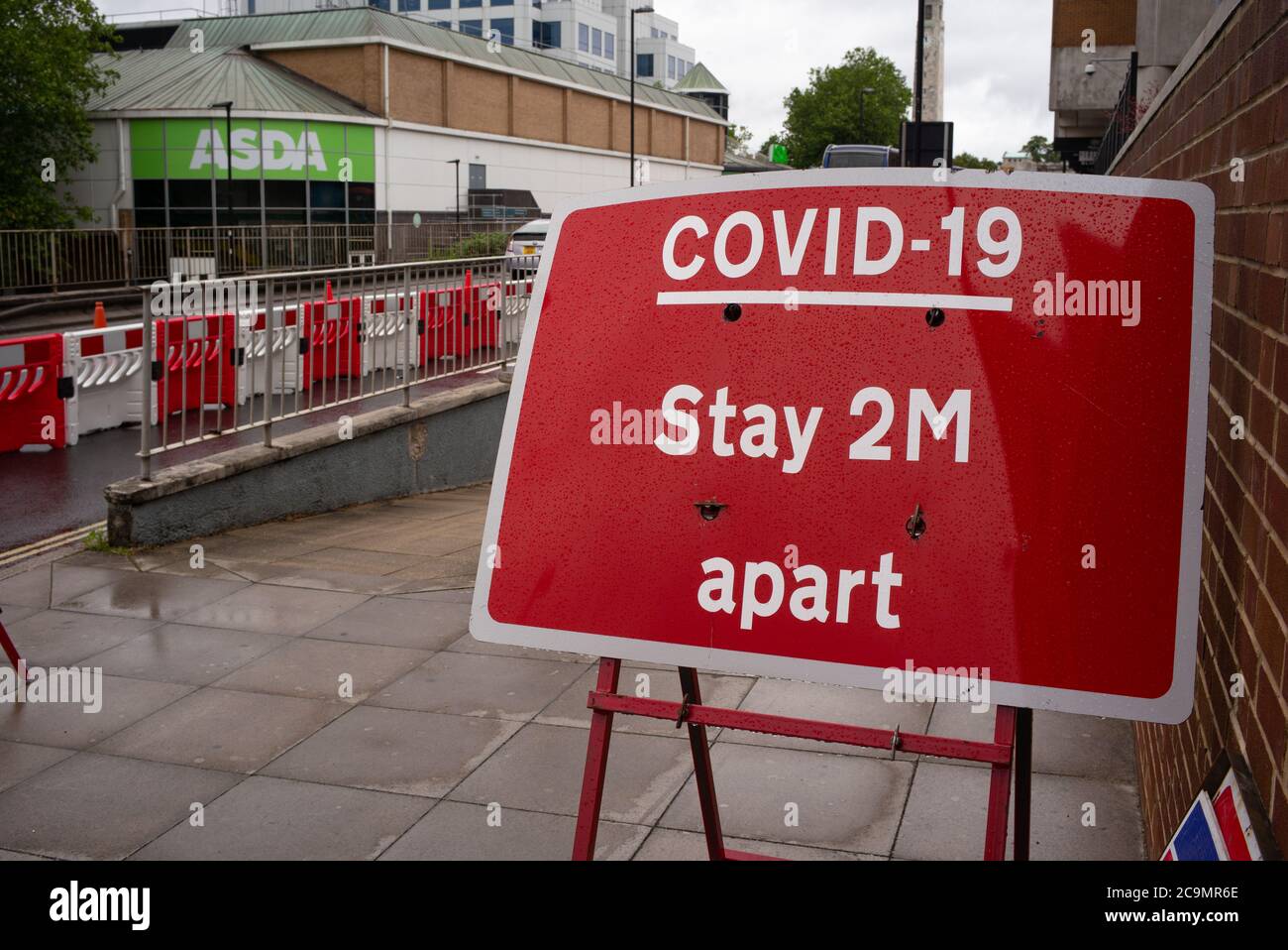 Covid-19 Virus Aufenthalt 2m auseinander Straßenschild außerhalb Asda in Southampton City England. Stockfoto