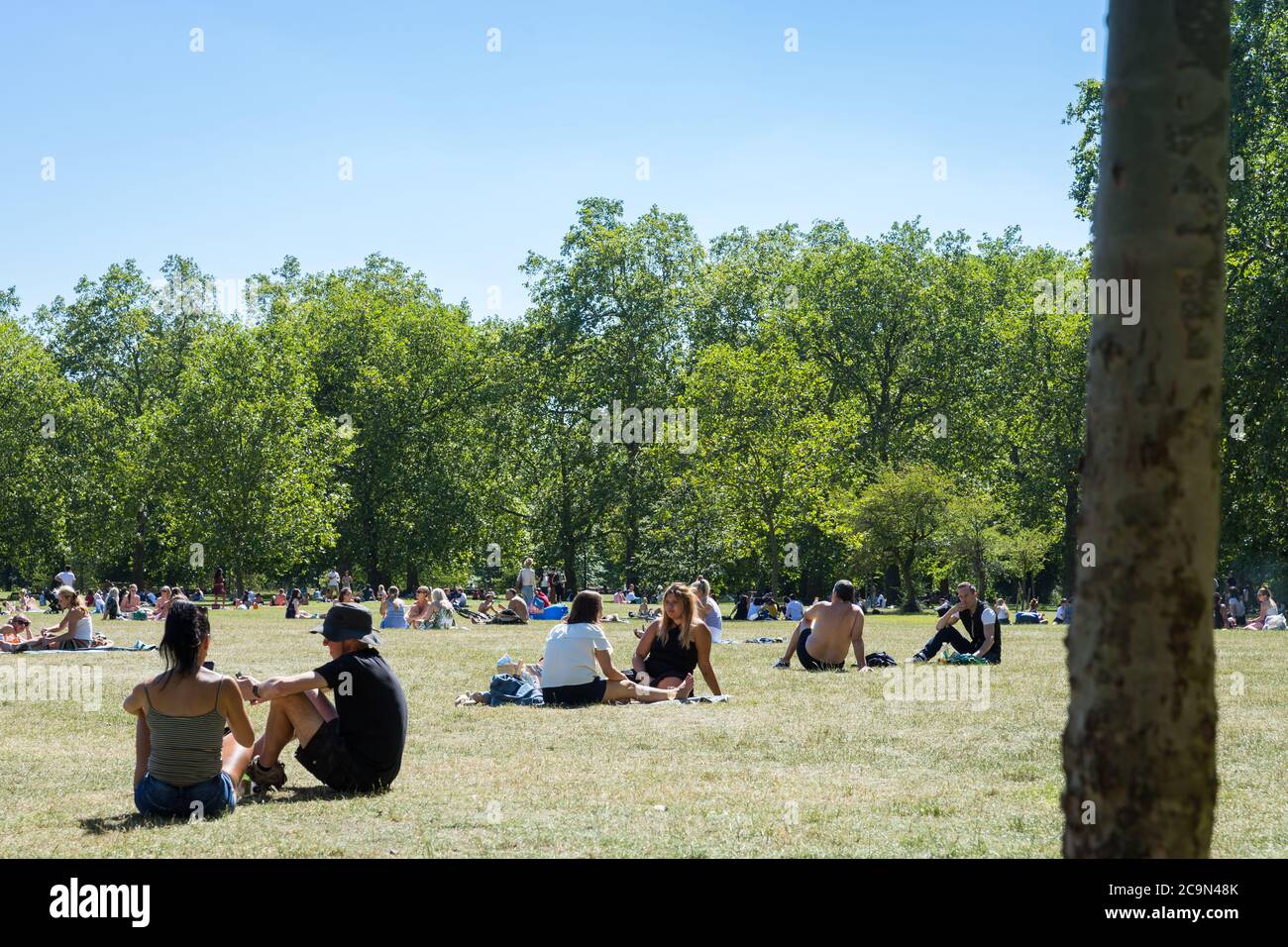 Menschen, die sich an einem sonnigen Tag in einem Park sozial distanzieren Stockfoto
