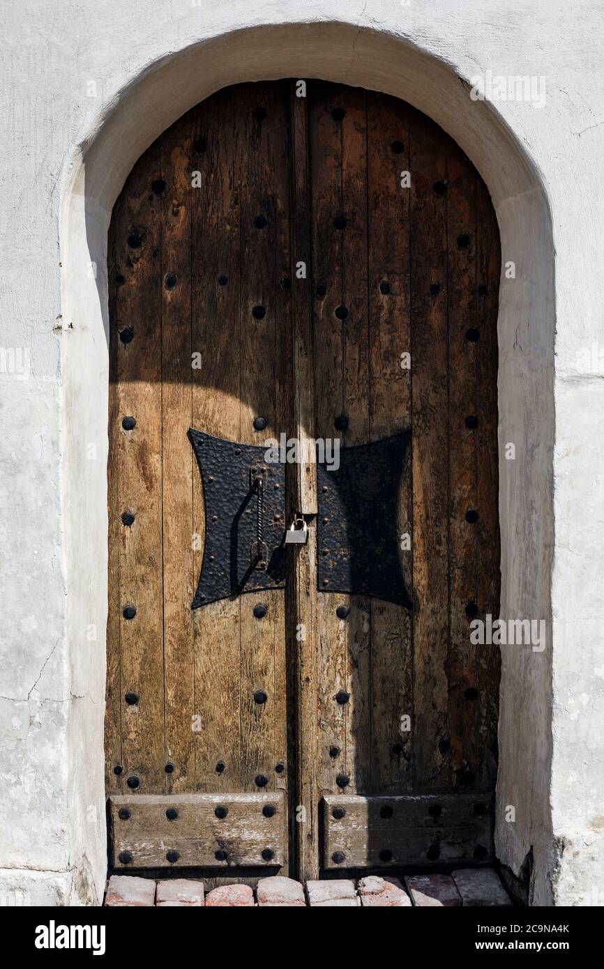 Antike Holztür mit geschmiedetem Griff und Vorhängeschloss im historischen Gebäude aus weißem Kalkstein Stockfoto