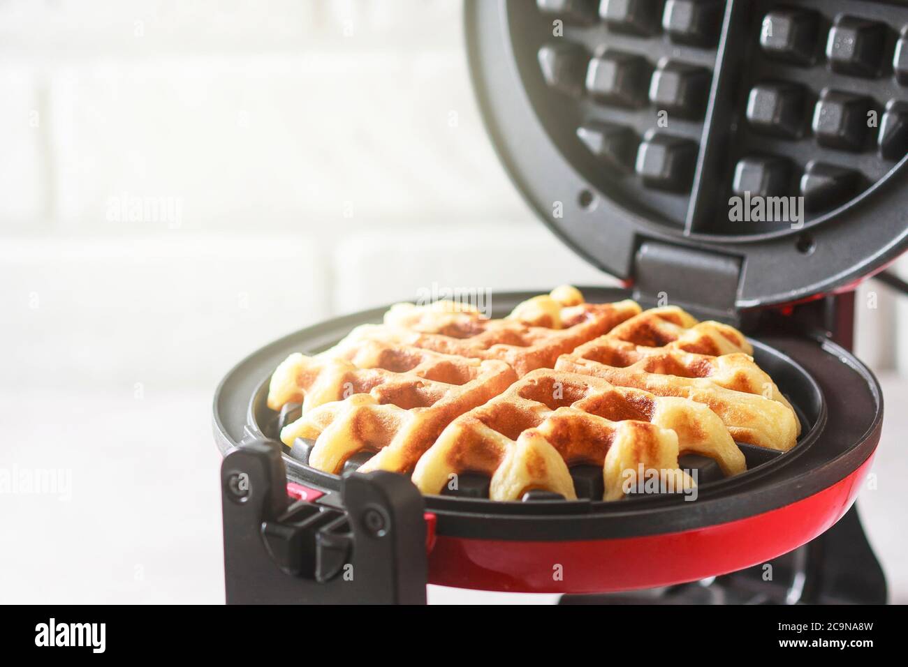 Der Prozess der Herstellung von hausgemachten Waffeln. Frisch gebackene Waffeln in einem Waffeleisen. Selektiver Fokus Stockfoto