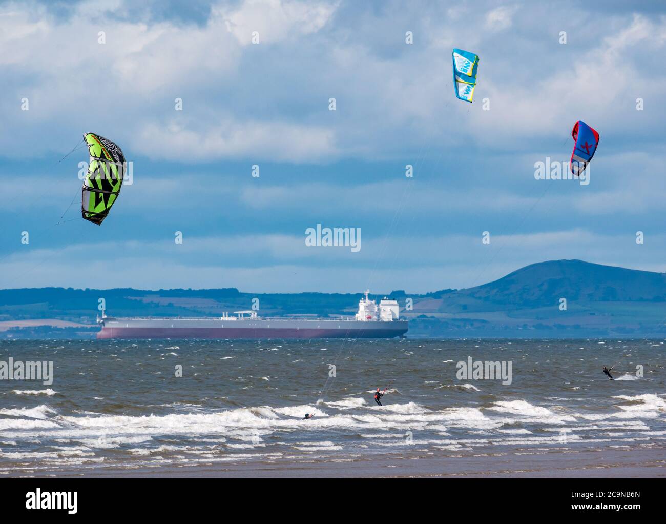 Kitesurfer Kitesurfen an windigen Tagen mit Tanker vor Anker am Horizont in Firth of Forth, Schottland, Großbritannien Stockfoto