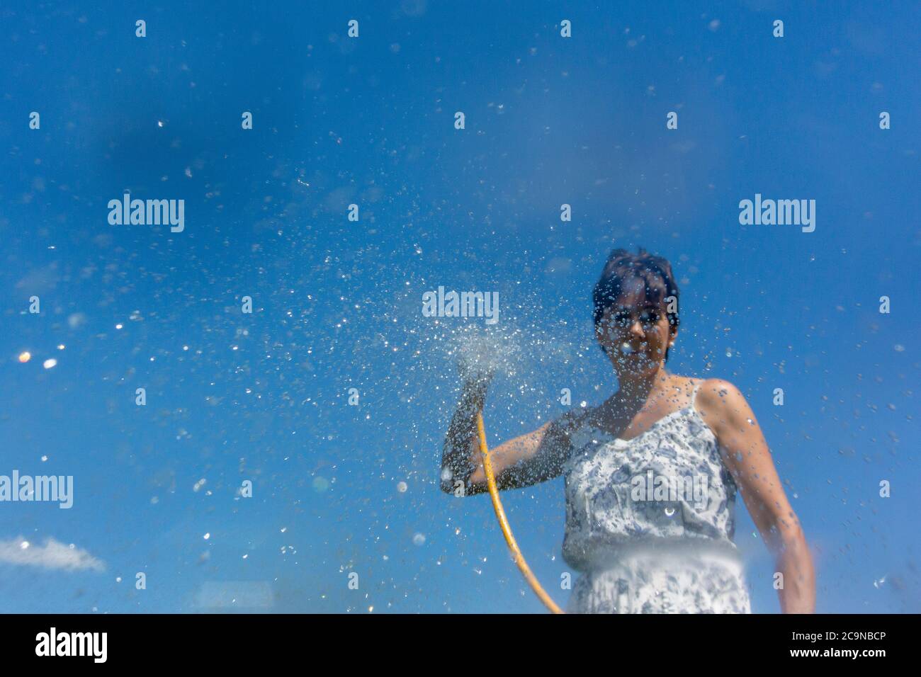 Frau, die Wasser aus einem Schlauch sprüht. North Yorkshire, Großbritannien. Stockfoto