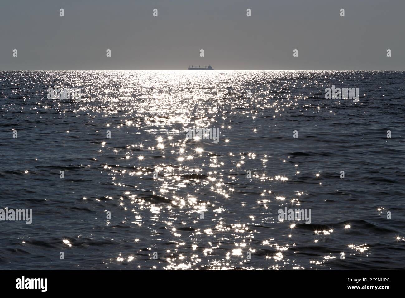 Eine Silhouette des Frachtschiffes weit entfernt im Meer an sonnigen Tagen Stockfoto