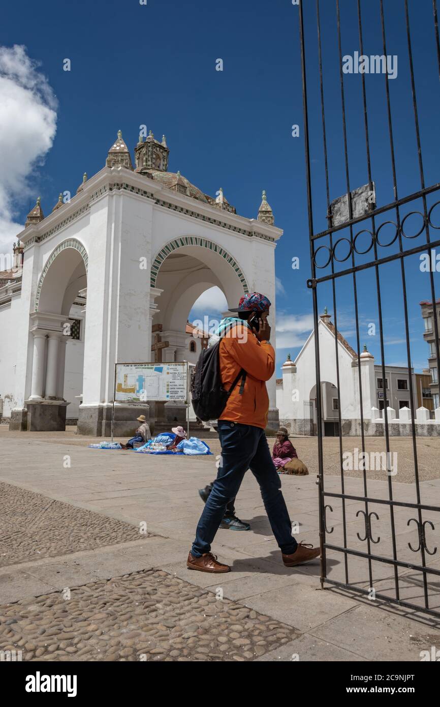 COPACABANA, BOLIVIEN - 16. JANUAR 2016: Ein nicht identifizierter Mann benutzt sein Handy, während er vor der Basilika unserer Dame von Copacabana in Bo läuft Stockfoto