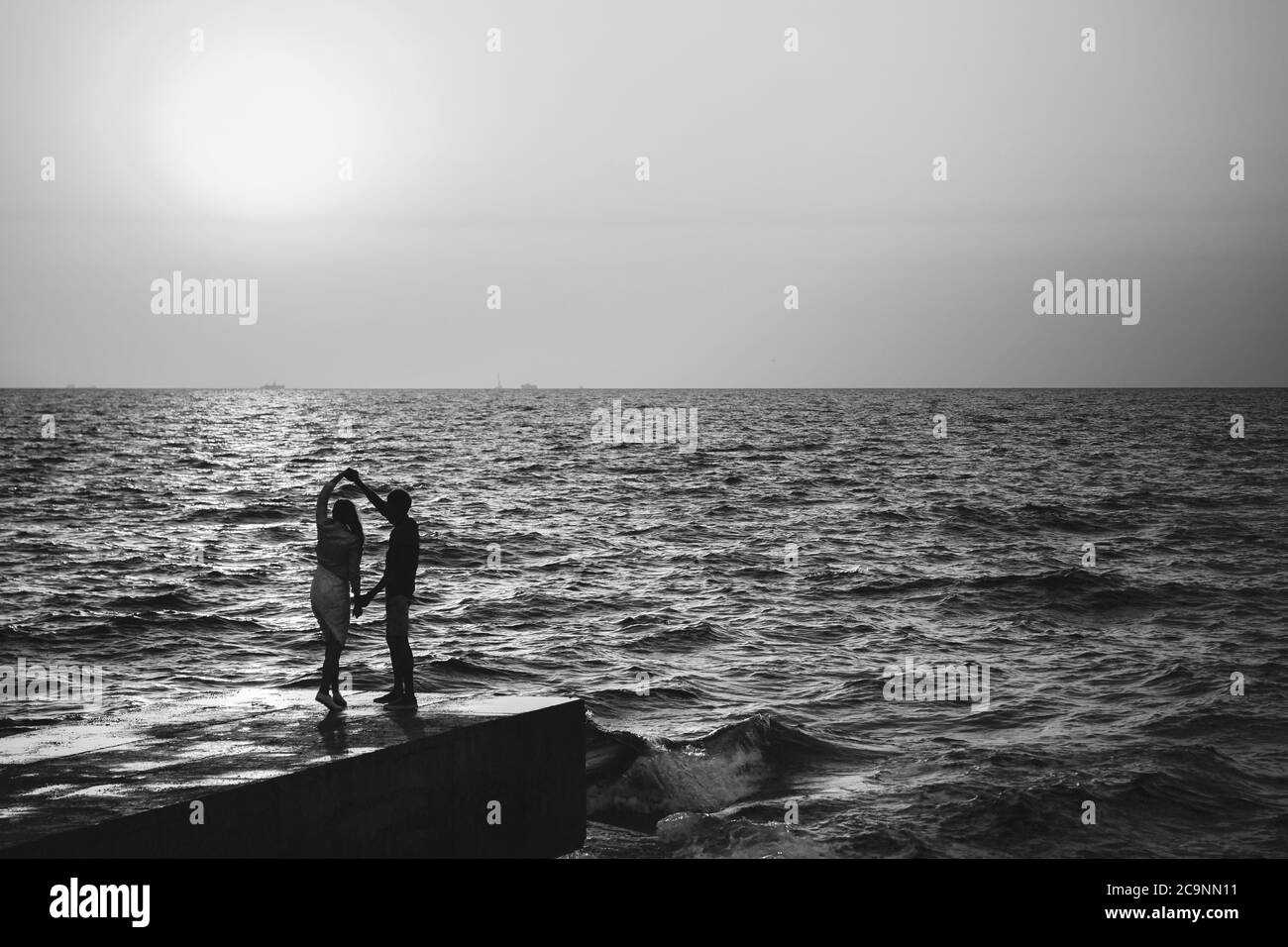 Junges Paar, das im Sommer am Pier am Strand tanzt Stockfoto
