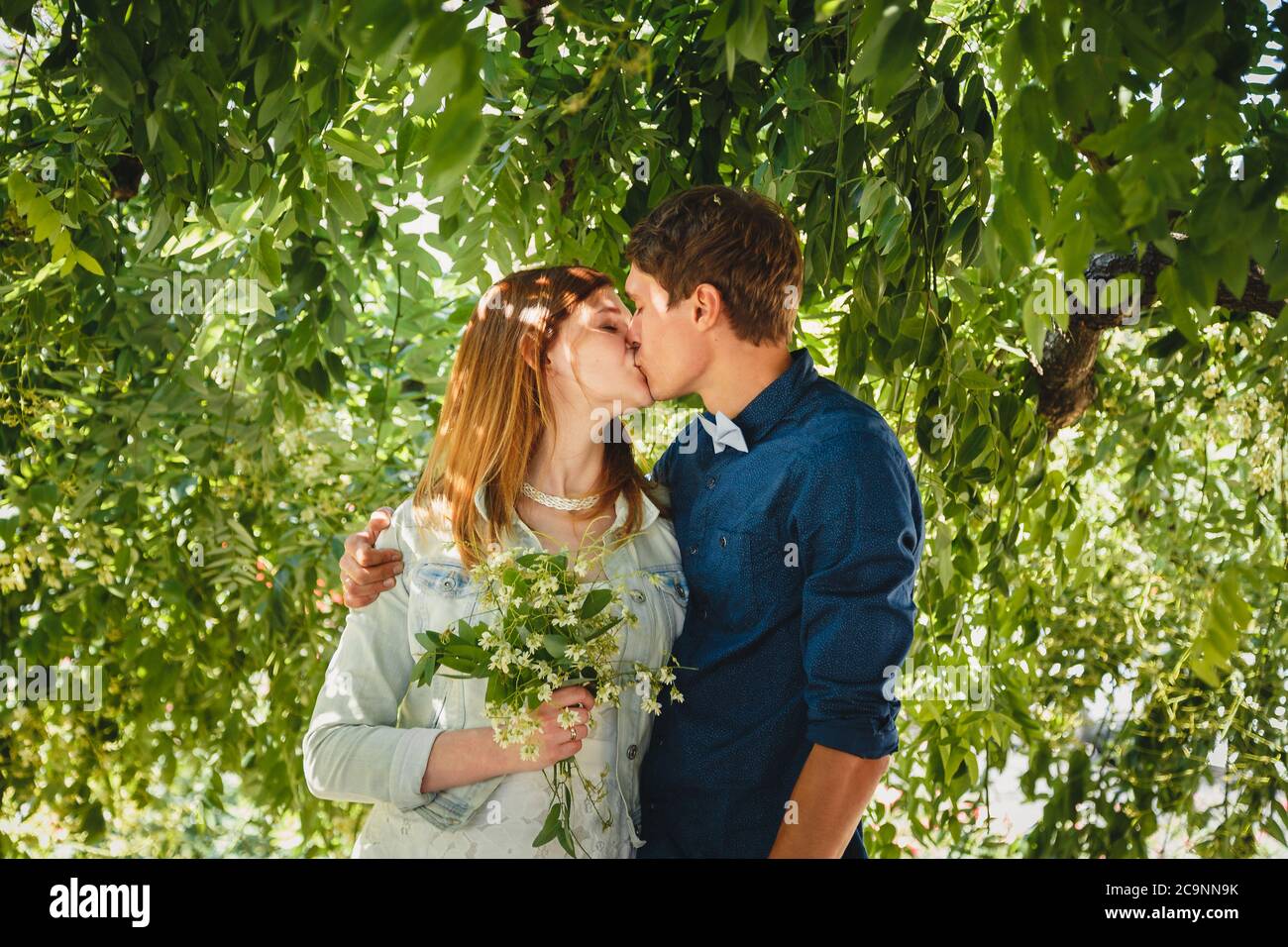 Happy stilvolle liebevolle Paar Hipster Umarmung und küssen in einem Park Stockfoto