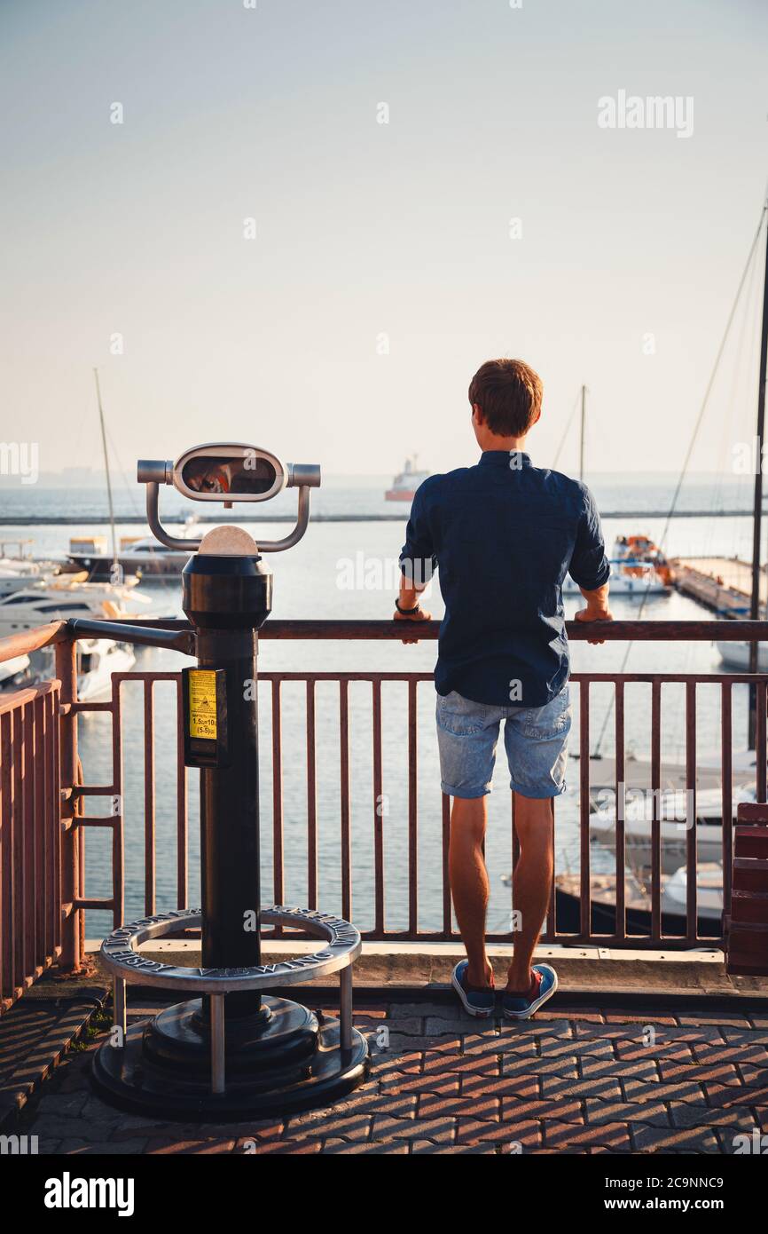 ODESSA, UKRAINE - 06. AUGUST 2015: Junger Mann, der sich vom Aussichtspunkt Hi Spy Viewing Machine am Hafen freut, Rückansicht Stockfoto