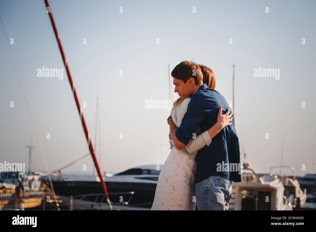 Nettes junges schönes Paar umarmt am Pier am Hafen mit kleinen Yachten, Hipster Stockfoto