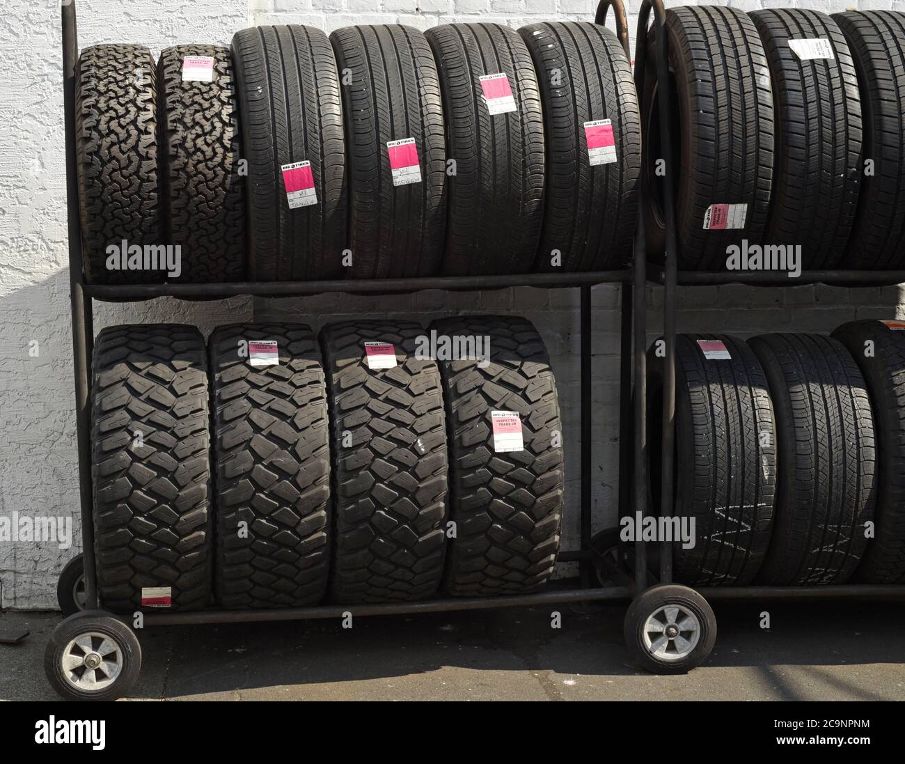 Neue Reifen zum Verkauf auf einem Regal außerhalb eines Reifenladens Stockfoto