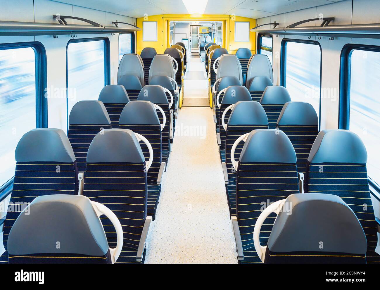 Personenzug Innenraum mit leeren Sitzen auf zwei Reihen, in Bewegung, in hellem Licht. Bahnreisen in Deutschland. Moderne öffentliche Verkehrsmittel. Keine Reisenden Stockfoto