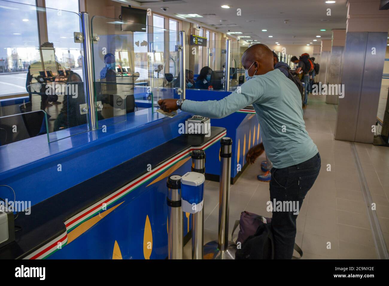 Ein Passagier mit Gesichtsmask aus Kigali, Ruanda, steht Schlange, als er auf die Abfertigung durch Einwanderungsbeamte am Jomo Kenyatta International Airport in Nairobi wartet. Kenya Airways hat die internationalen Flüge nach der Lockerung der Reisebeschränkungen durch Präsident Uhuru Kenyatta wieder aufgenommen. Die Flüge wurden während des Ausbruchs der Coronavirus-Pandemie im Land gestoppt. Stockfoto