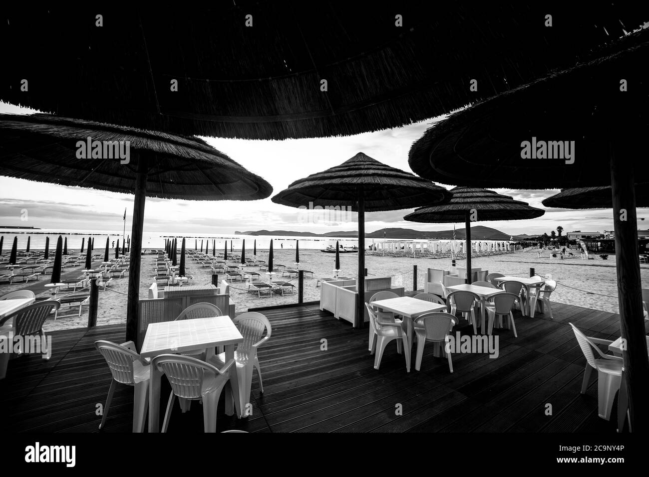 Sonnenschirme, Tische und Stühle am Meer in Sardinien, Italien. Schwarz-Weiß-Effekt Stockfoto