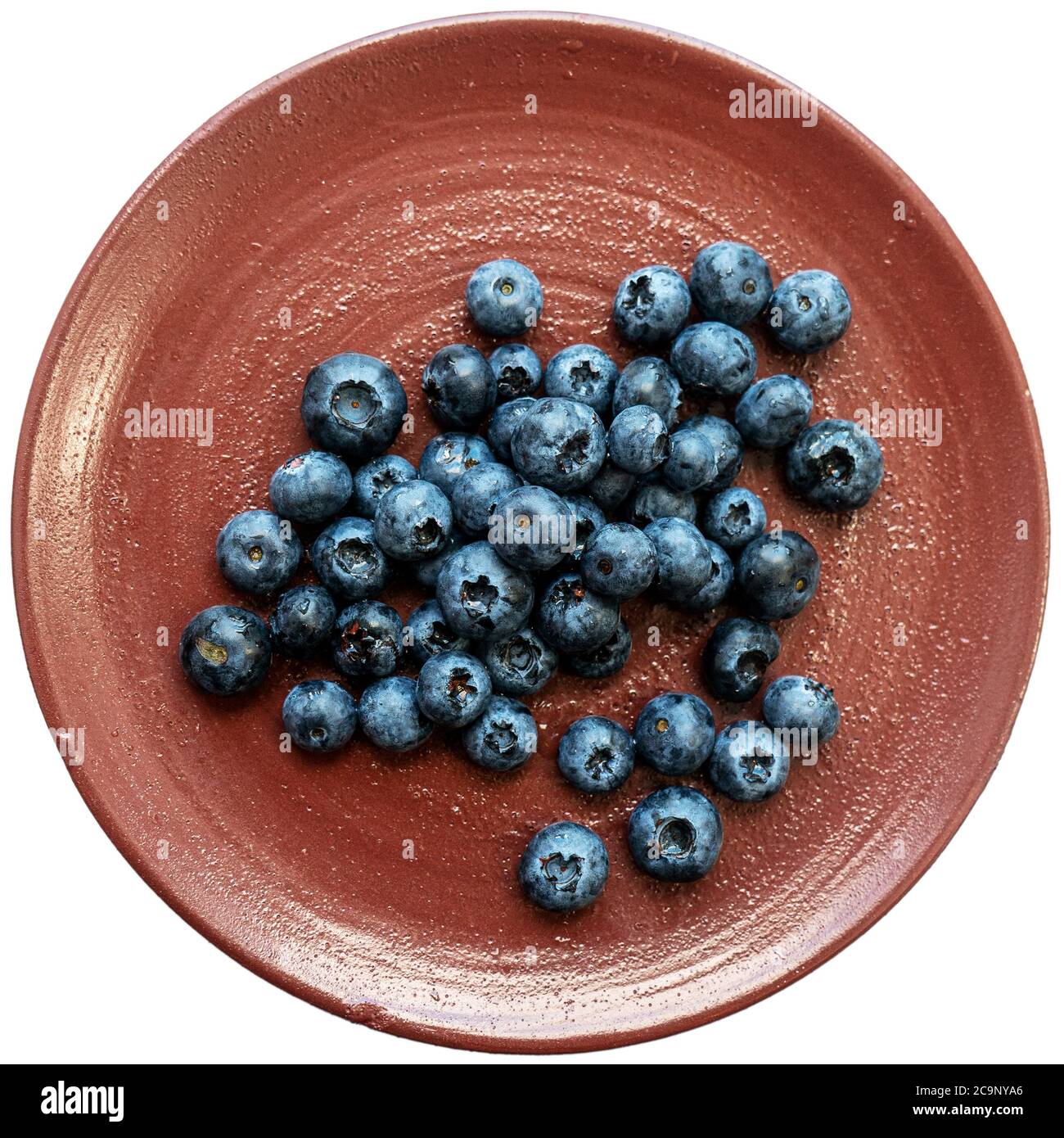 Frische Brombeeren oder Blaubeeren in einer braunen Tontafel, fotografiert von oben. Nahaufnahme von frischen, gesunden Sommerbeeren. Stockfoto