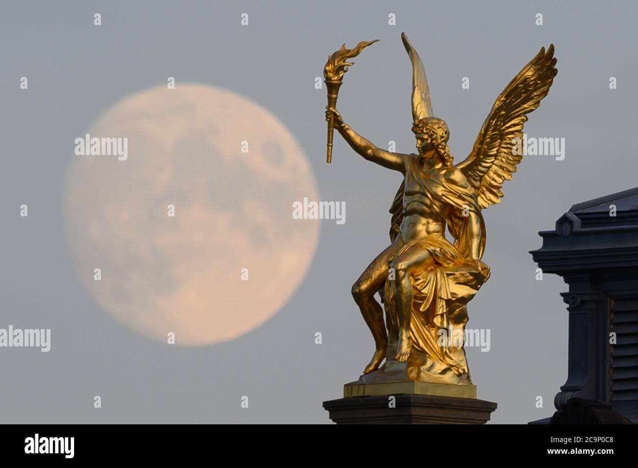 Dresden, Deutschland. August 2020. Der Mond steigt hinter einer vergoldeten Engelsfigur auf dem Dach der Hochschule für Bildende Künste (HfBK) auf. Quelle: Sebastian Kahnert/dpa-Zentralbild/dpa/Alamy Live News Stockfoto