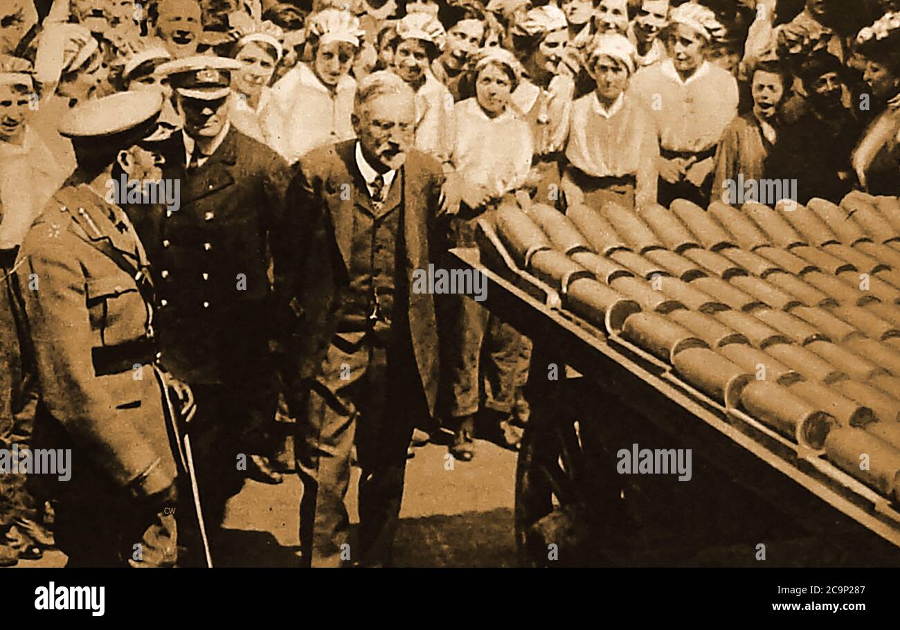 Der erste Weltkrieg - der König (George V) besucht im Januar 1917 eine britische Munitionsfabrik. Während Arbeiterinnen ihn beobachten, wie er einen Wagen voller Muscheln untersucht. Stockfoto