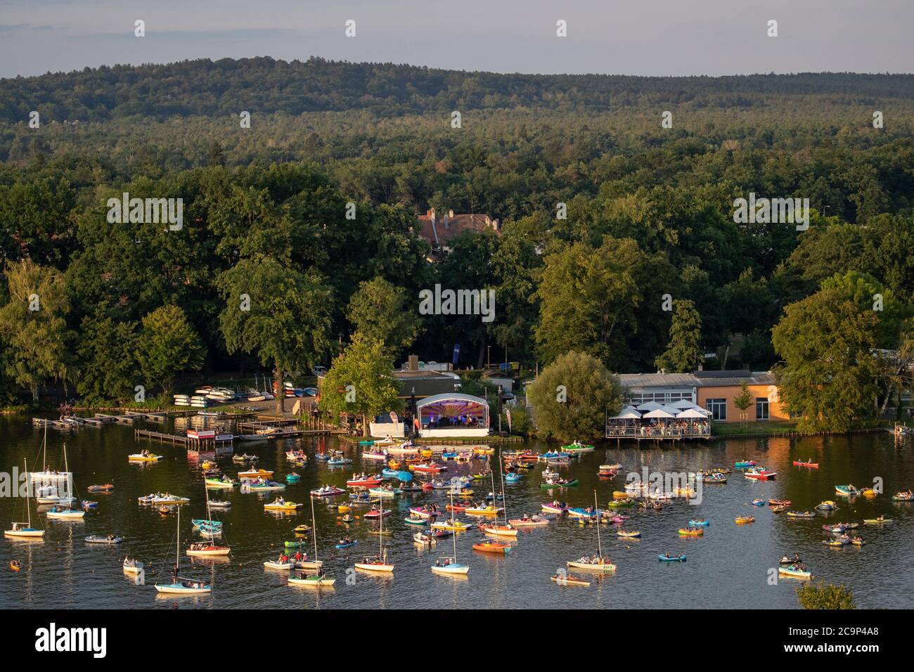 01. August 2020, Bayern, Nürnberg: Die Staatsphilharmonie (h, M) spielt auf der Seestufe auf dem Großen Dutzendteich ein Konzert vor Zuschauern, die das Konzert auf eigenen Booten verfolgen. Aufgrund der musikalischen Veranstaltungen Bardentreffen, Klassik Open Air und Stars in Luitpoldhain, die aufgrund von Corona abgesagt wurden, hat das Projektbüro im Kulturbereich der Stadt Nürnberg drei verschiedene Konzerte mit einem Open-Air-Konzertwochenende am Ufer des Dutzendteichs organisiert. Das einzigartige Angebot soll als Brückenhilfe und Experiment in einem dienen. Das Publikum wird ihr o mitbringen müssen Stockfoto