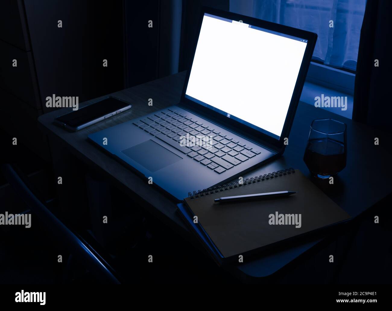 WFH - Überstunden und Arbeit von zu Hause spät in der Nacht auf Laptop mit Glas Whisky 2 Stockfoto
