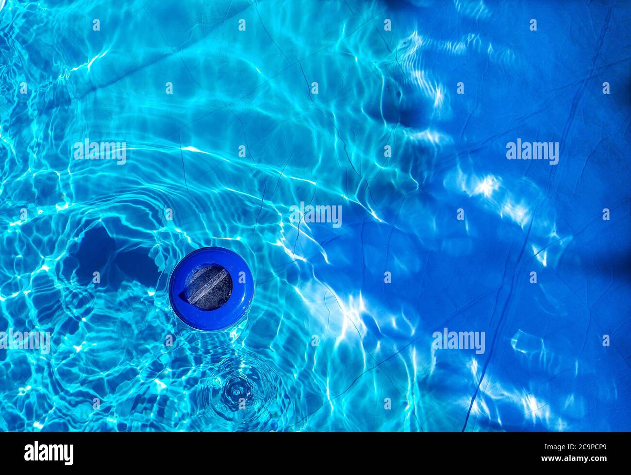 Schwimmende Kunststoff-Chlorspender und blaues Wasser von oben gesehen. Chlorspender wird verwendet, um das Schwimmbad zu desinfizieren Stockfoto