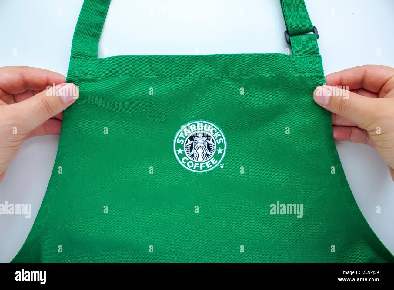 Calgary, Alberta, Kanada. August 2020. Ein Starbucks Mitarbeiter, der eine Schürze mit Markenlogos im Laden hält. Stockfoto