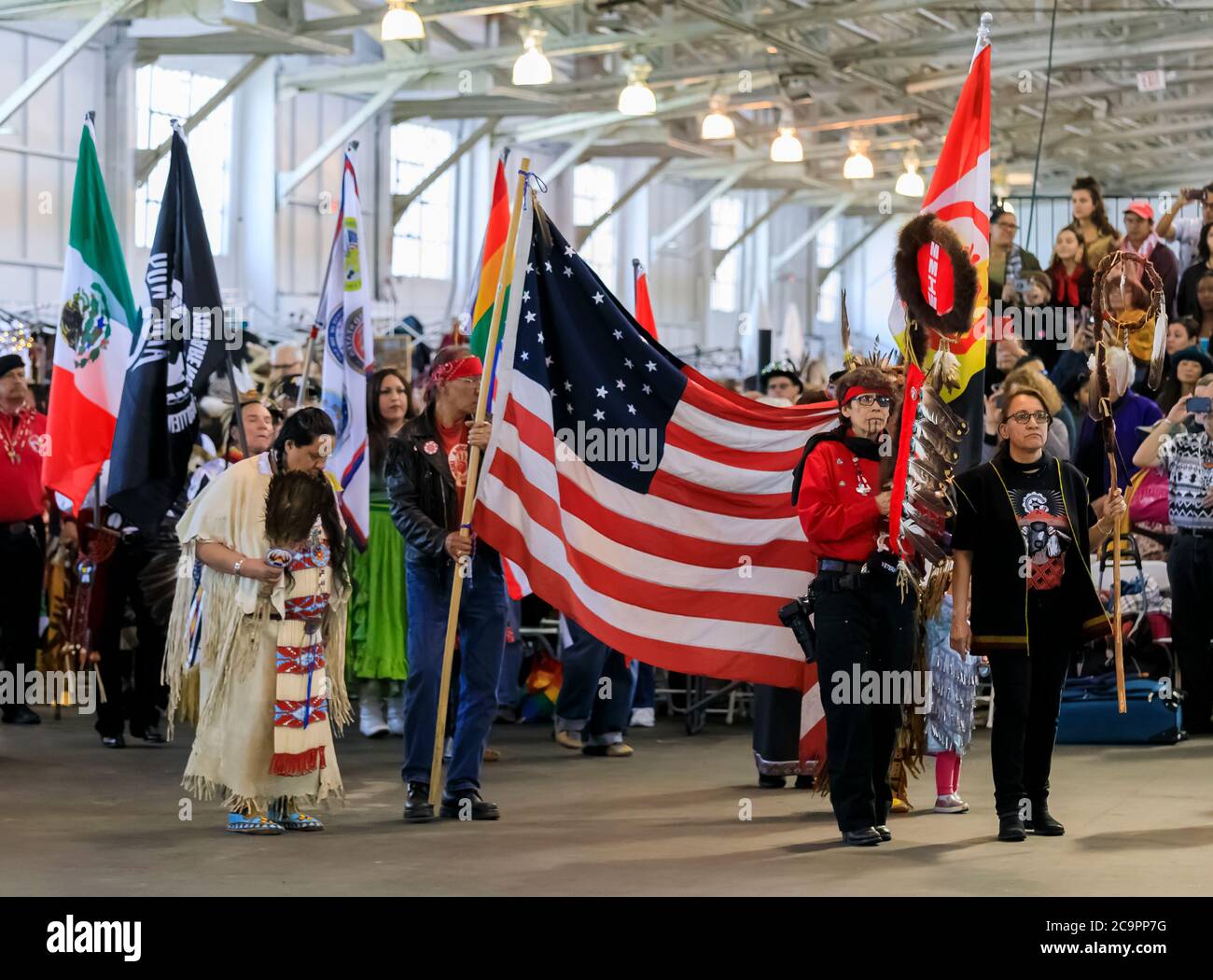 San Francisco, USA - Februar 08 2020: Indianer in traditionellen Outfits tragen traditionelle Adlerstab und Flaggen bei powwow Grand Entry Stockfoto