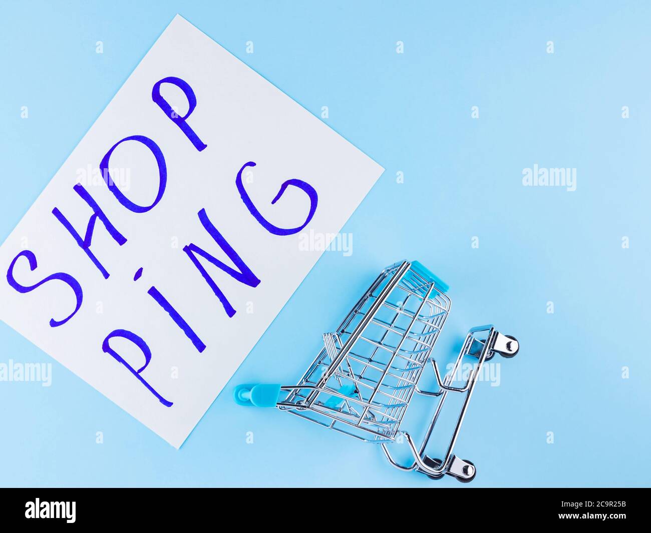 Warenkorb auf blauem Hintergrund. Shop Trolley im Supermarkt. Verkauf und Rabatt. Trend der Konsumgesellschaft. Konzept des Einkaufens. Speicherplatz kopieren. Draufsicht Stockfoto