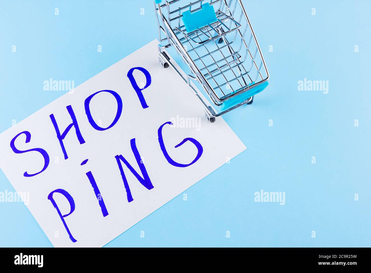Warenkorb auf blauem Hintergrund. Shop Trolley im Supermarkt. Verkauf und Rabatt. Trend der Konsumgesellschaft. Konzept des Einkaufens. Speicherplatz kopieren. Draufsicht Stockfoto
