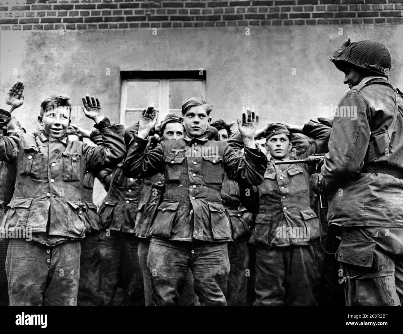 Ein amerikanischer Soldat steht Wache über einer Gruppe deutscher Gefangener 1945 Stockfoto