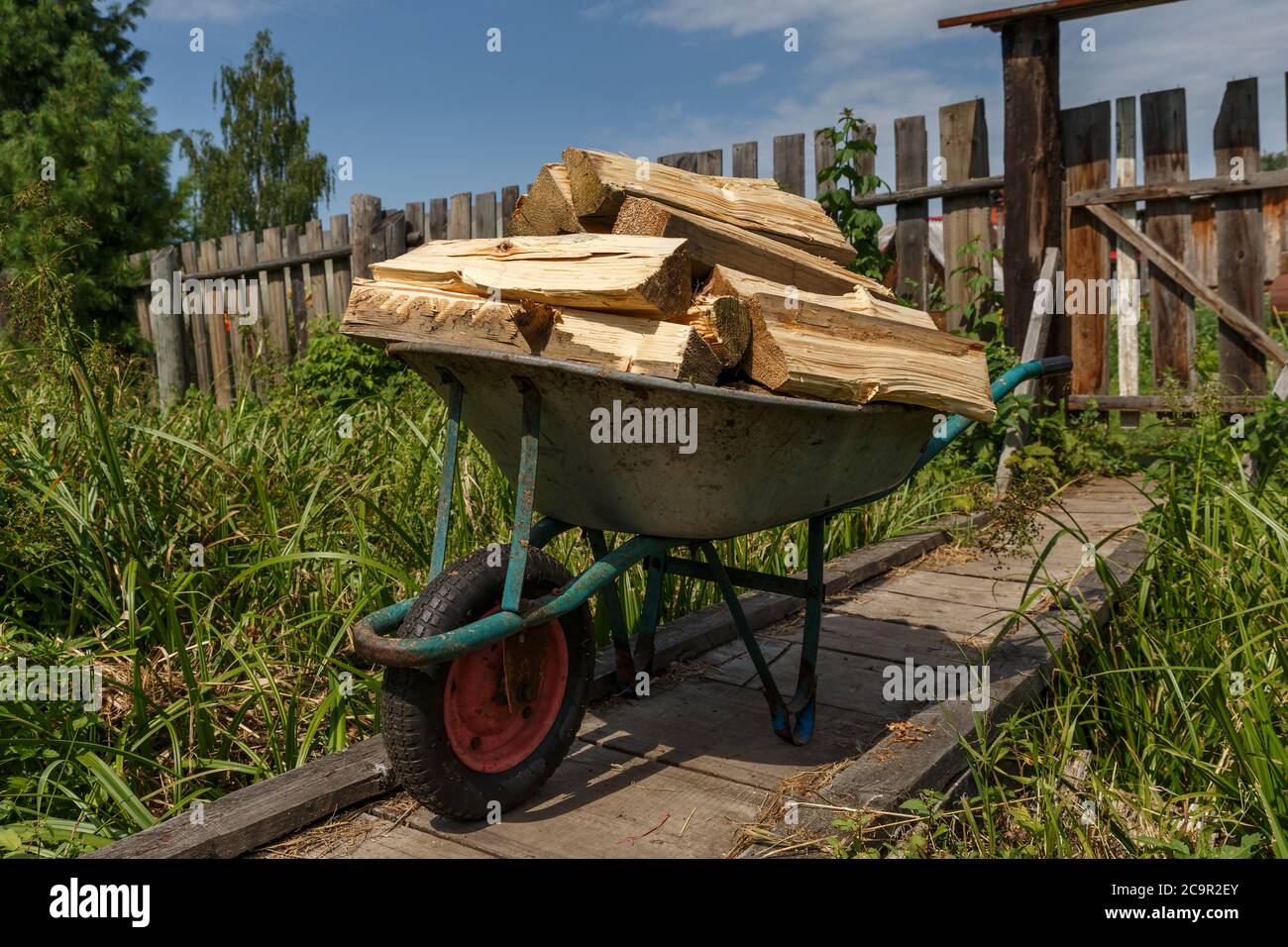 Ein Gartenwagen mit gehacktem Holz steht auf einer Holzbrücke. Stockfoto