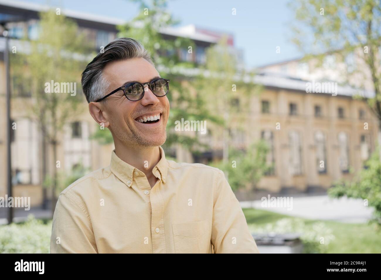 Porträt eines hübschen reifen Mannes, der stilvolle Brillen trägt, auf der Straße geht, lacht. Positives Lifestyle-Konzept Stockfoto