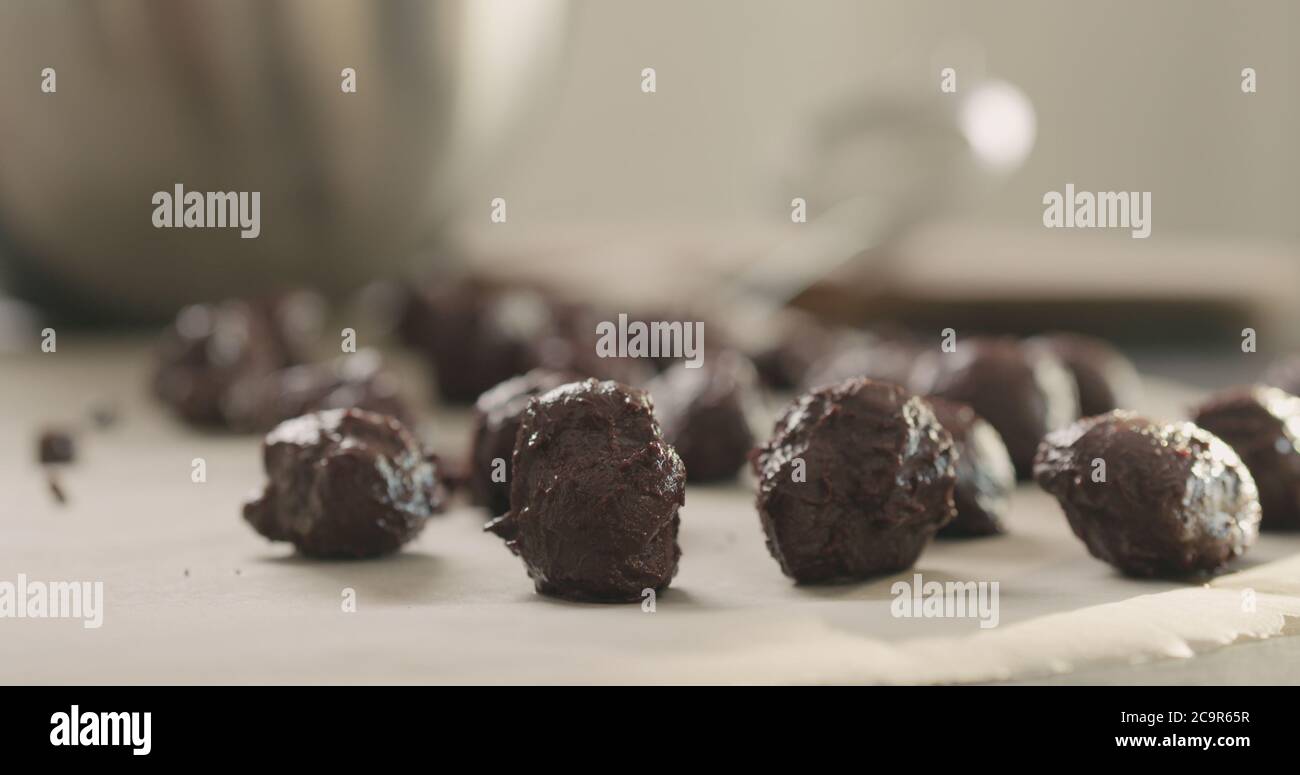 Junge Frau, die Schokoladentrüffel auf heimigeren Kictchen zubereitet Stockfoto