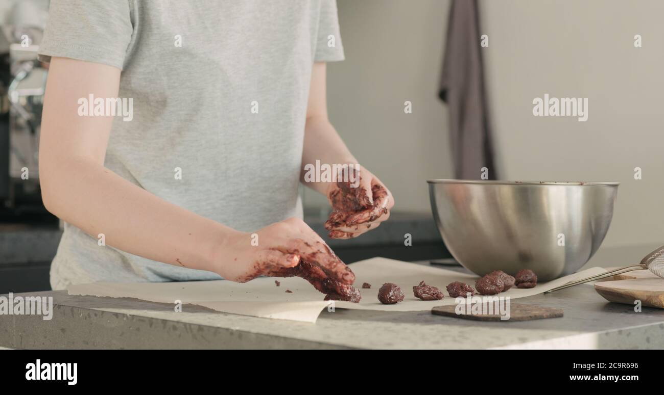 Junge Frau, die Schokoladentrüffel auf heimigeren Kictchen zubereitet Stockfoto