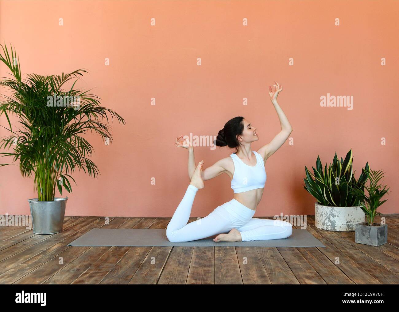 Junge Brünette weiblich in weißen Sportswear auf Matte und tun Yoga, während Achtsamkeit üben Stockfoto